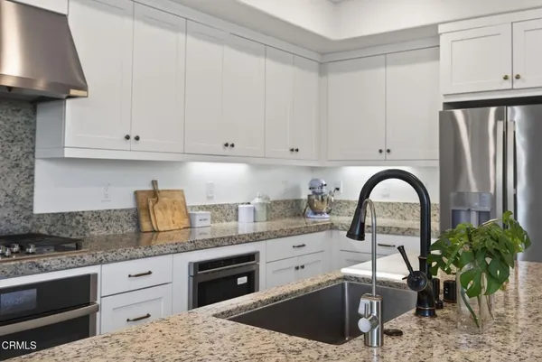 a kitchen with granite countertop a sink stainless steel appliances and cabinets