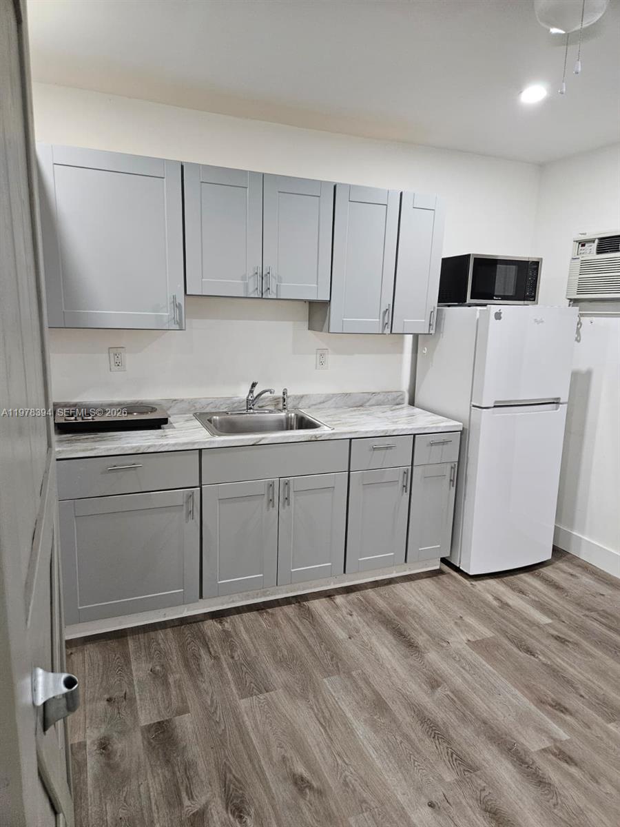 2862 Southwest 38th Court Miami, FL 33134 - Photo 49 of 67 a kitchen with stainless steel appliances granite countertop a sink a stove a refrigerator with white cabinets and wooden floor