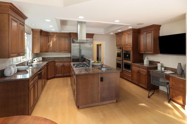 a kitchen with stainless steel appliances kitchen island granite countertop a sink and a refrigerator