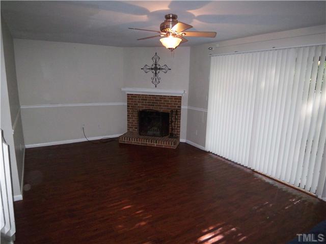 7300 Sandy Creek Drive Raleigh, NC 27615 - Photo 11 of 25 a view of a livingroom with a fireplace a chandelier fan and wooden floor