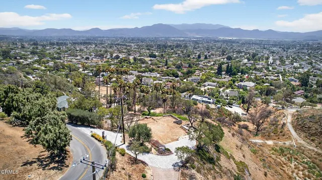 an aerial view of residential house with yard and mountain view in back