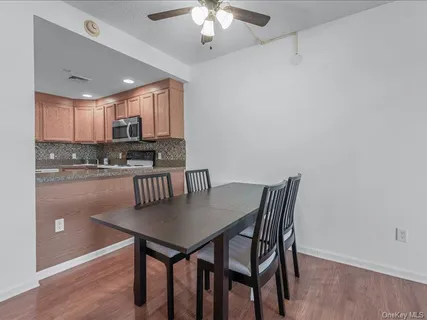 a kitchen with stainless steel appliances granite countertop a dining table chairs and a refrigerator