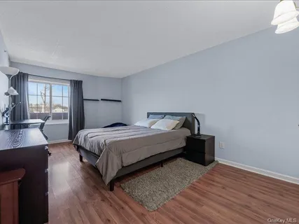 a bedroom with a bed lamp on wall and a large window