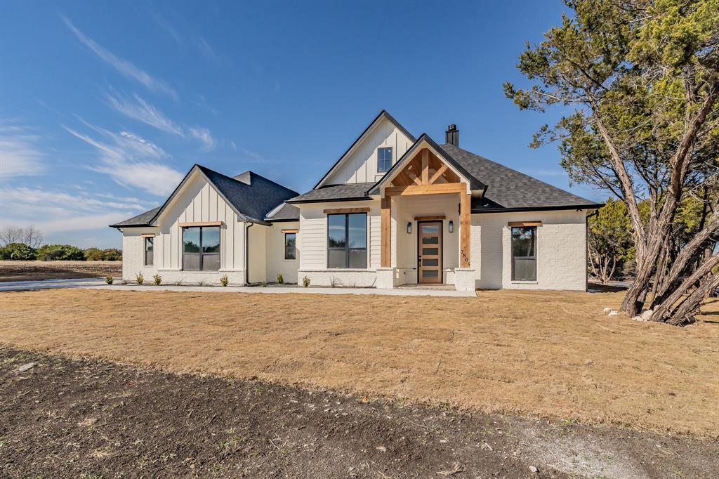 7805 Kenleigh Lane Rio Vista, TX 76093 - Photo 3 of 40 Modern inspired farmhouse with board and batten siding, a chimney, a front yard, and covered porch