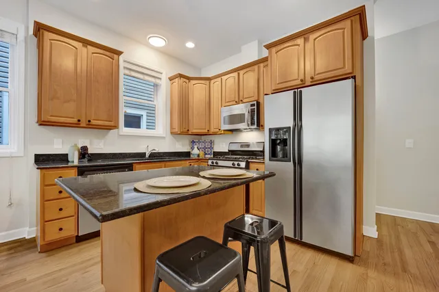 a kitchen with stainless steel appliances granite countertop a refrigerator a stove and a sink with wooden floor