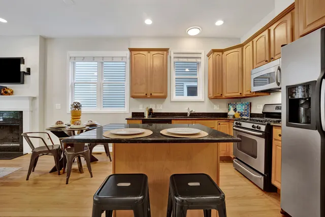 a kitchen with stainless steel appliances granite countertop a sink a stove a refrigerator cabinets and chairs