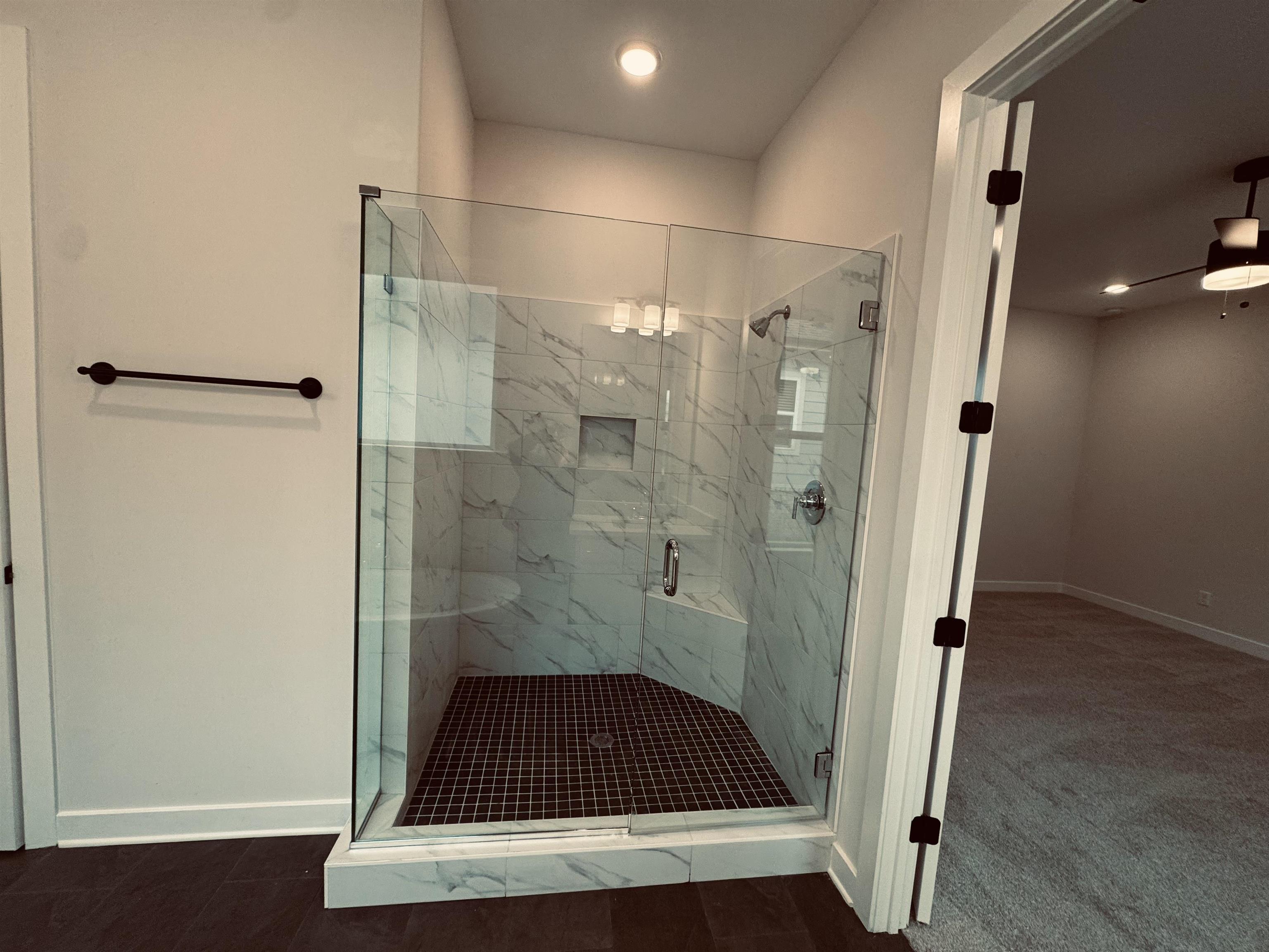 Bathroom featuring ceiling fan and a shower with door