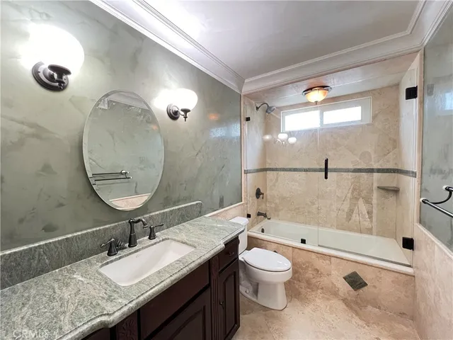 a bathroom with a granite countertop sink a toilet a mirror and shower