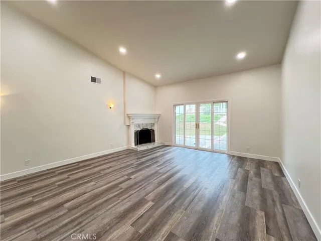 a view of empty room with wooden floor and fireplace