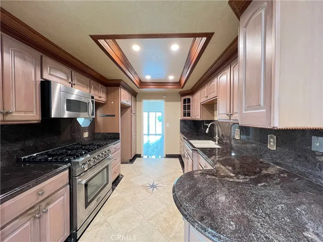 a kitchen with stainless steel appliances granite countertop a stove a sink and a microwave