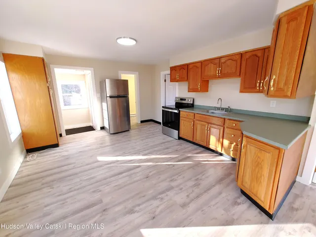 a kitchen with stainless steel appliances granite countertop a refrigerator a sink dishwasher a stove and white countertops with wooden floor