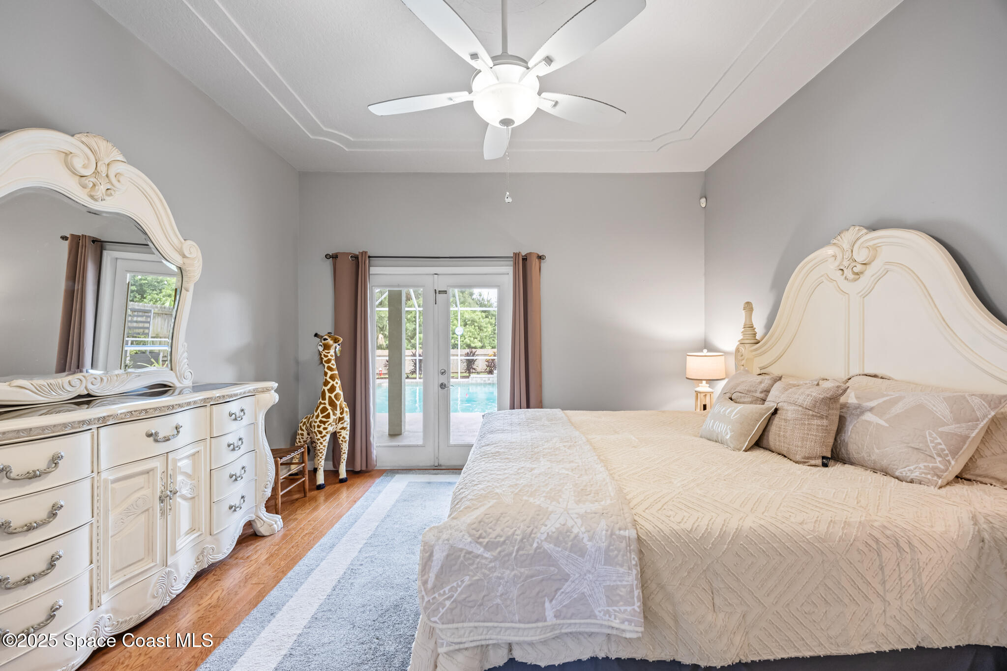 1252 Winding Meadows Road Rockledge, FL 32955 - Photo 21 of 32 a spacious bedroom with a bed a dresser and a chandelier