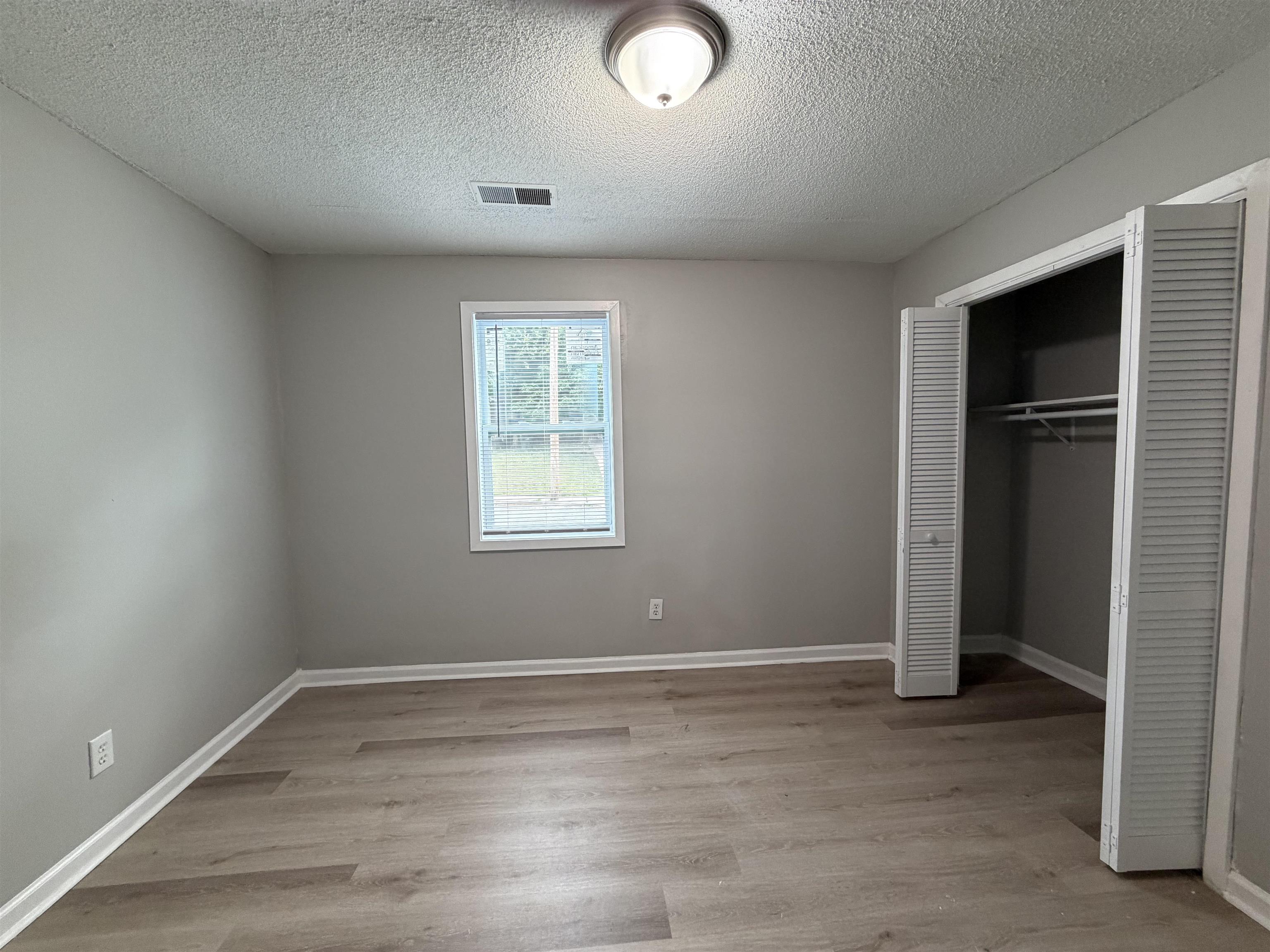 945 Nora Road Memphis, TN 38109 - Photo 12 of 27 an empty room with wooden floor and windows
