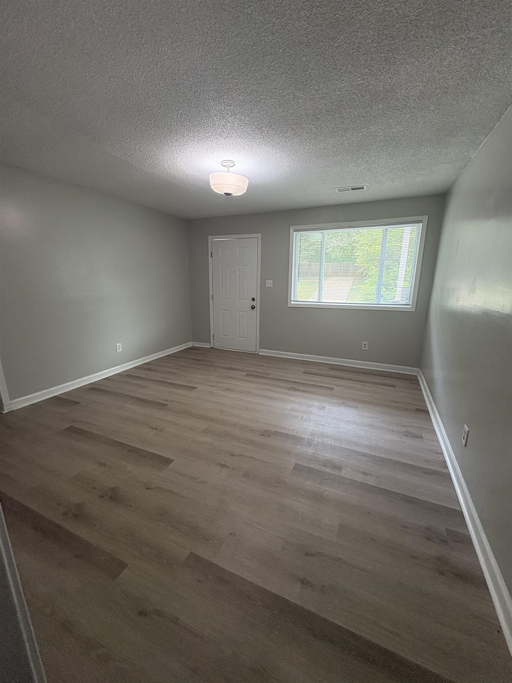 945 Nora Road Memphis, TN 38109 - Photo 7 of 27 an empty room with wooden floor and windows