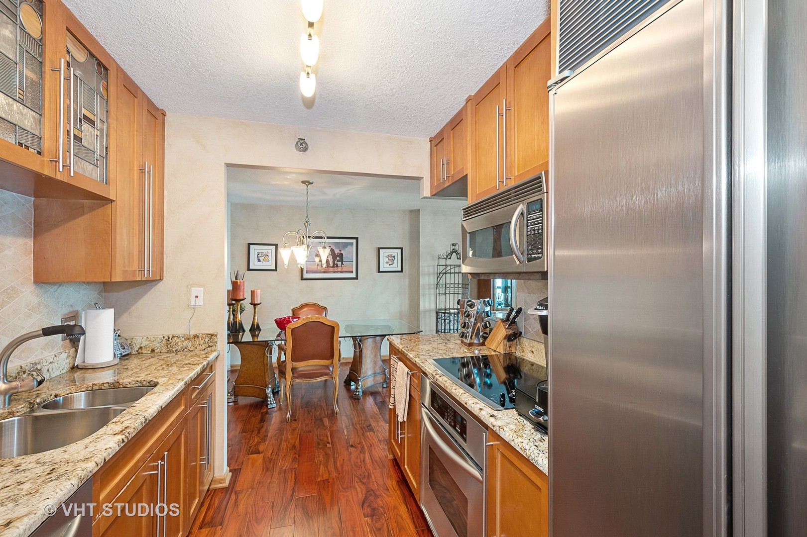 195 North Harbor Drive, Unit 5201 Chicago, IL 60601 - Photo 8 of 16 a kitchen with stainless steel appliances granite countertop a refrigerator a sink dishwasher a stove and a dining table with wooden floor