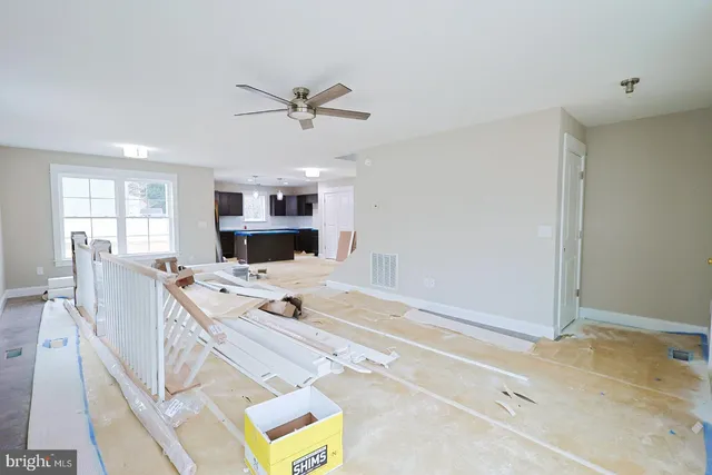 a living room with stainless steel appliances furniture a rug and a kitchen view