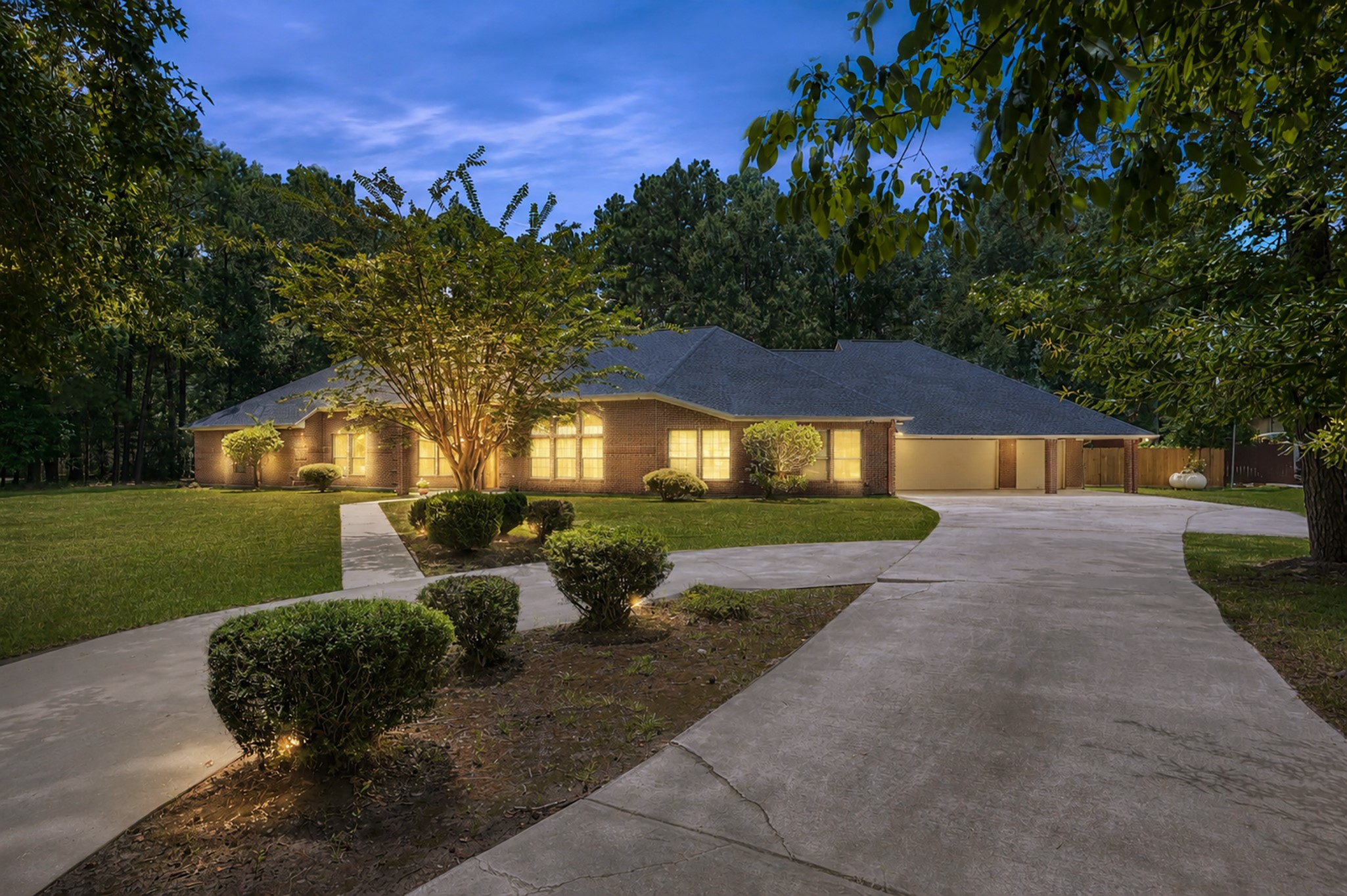 910 Commons Way Court Huffman, TX 77336 - Photo 1 of 49 A spacious, well-lit single-story brick home with a large driveway and manicured landscaping. It's set against a backdrop of mature trees, providing a serene and private atmosphere.