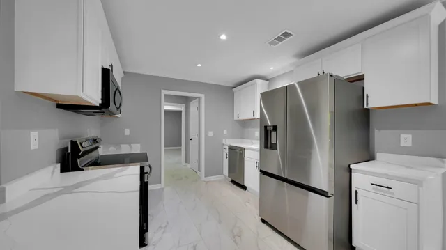 a kitchen with stainless steel appliances a refrigerator a sink and white cabinets