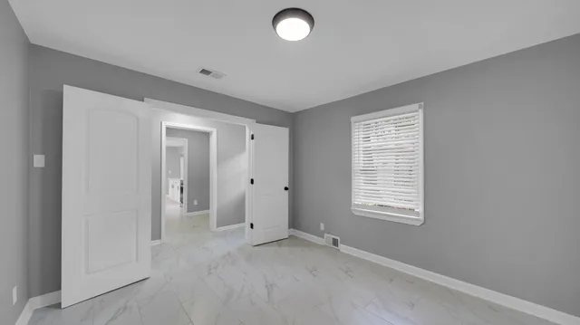 a view of an empty room with a window and closet area