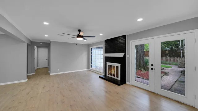 a view of a livingroom with a fireplace a ceiling fan and window