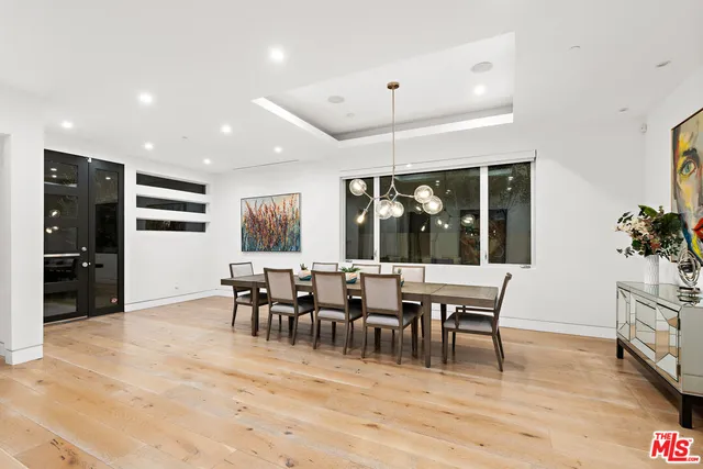 a dining room with wooden floor a chandelier a glass table and chairs