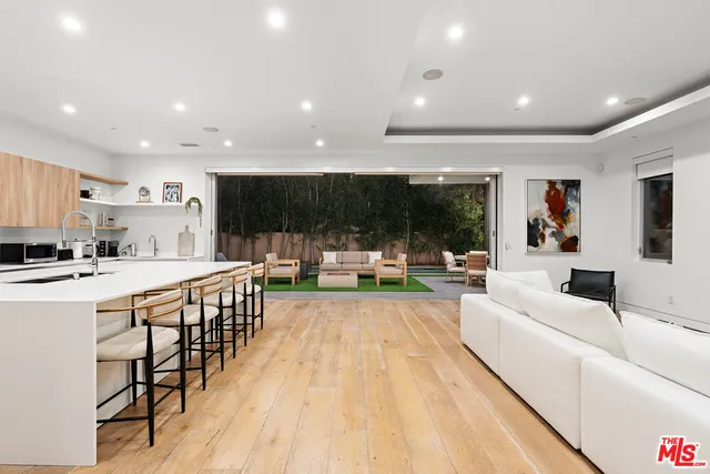 a living room with stainless steel appliances furniture kitchen view and a flat screen tv