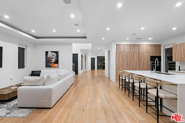 a living room with furniture wooden floor and a kitchen view