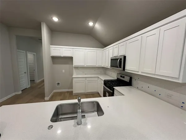 a kitchen with a sink a microwave and cabinets