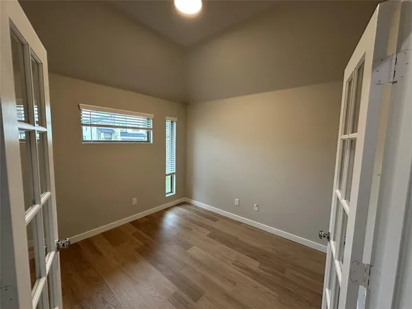 a view of an empty room with wooden floor and a window