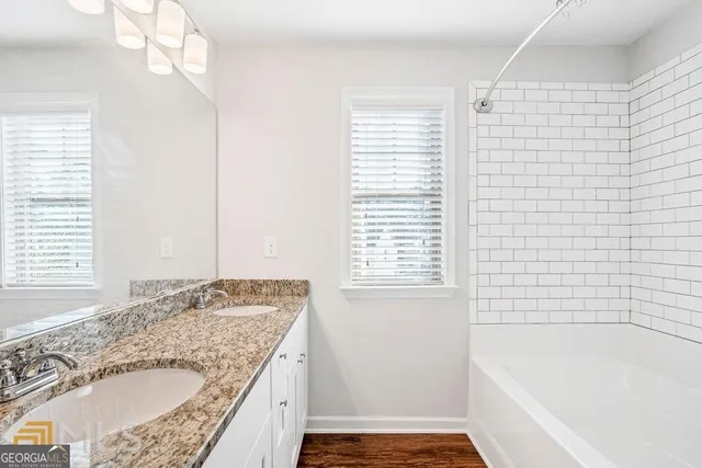 a bathroom with a granite countertop sink a bathtub and next to a window