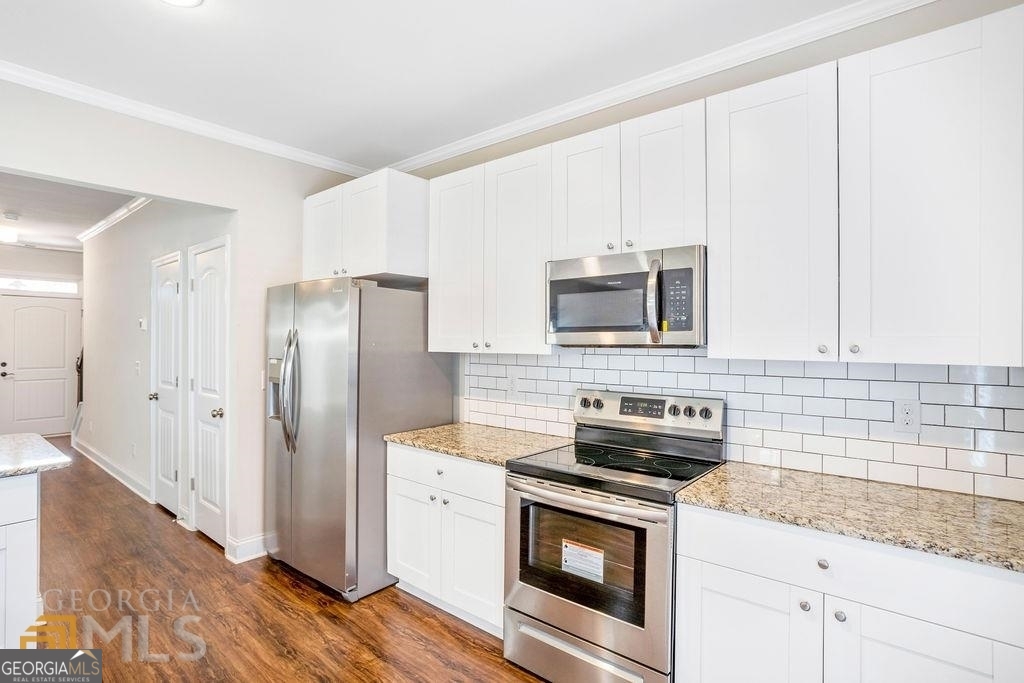 7704 Fawn Circle Covington, GA 30014 - Photo 8 of 14 a kitchen with granite countertop a refrigerator stove and microwave