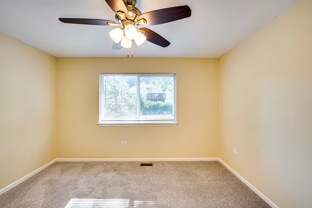 an empty room with a window and a fan