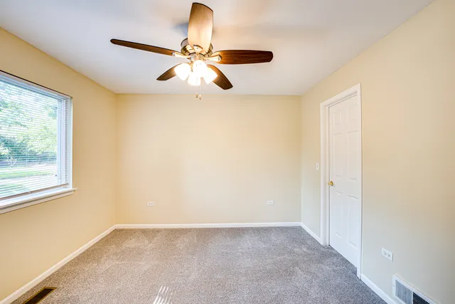 an empty room with windows and fan