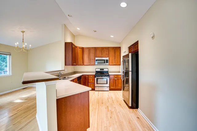 a kitchen with stainless steel appliances granite countertop a sink a stove a refrigerator cabinets and wooden floor
