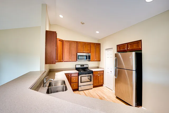 a kitchen with granite countertop a refrigerator a sink a stove and white cabinets