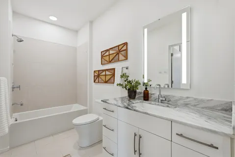 a bathroom with a granite countertop sink a toilet and shower