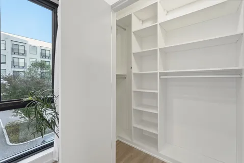 a view of a walk in closet with wooden floor