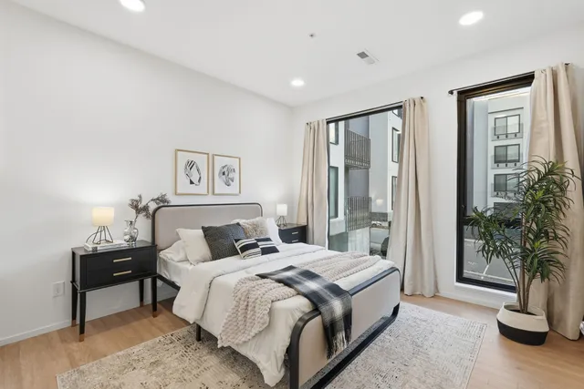 a spacious bedroom with a large bed and a potted plant