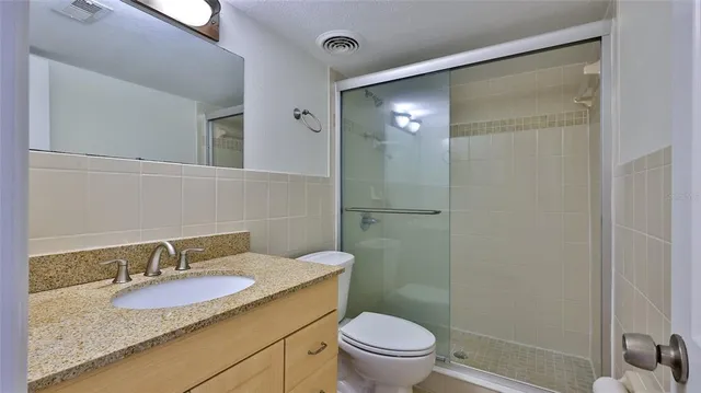 a bathroom with a granite countertop sink toilet and shower