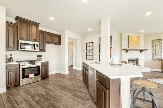 a kitchen with kitchen island a stove a sink a oven a dining table and chairs