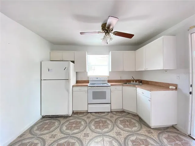 a kitchen with a refrigerator a stove top oven and white cabinets