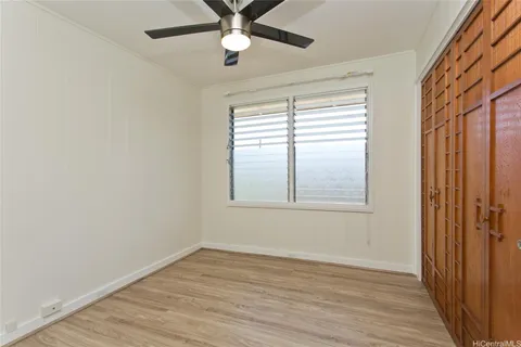 an empty room with wooden floor fan and windows