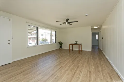 a view of an empty room with a window and wooden floor