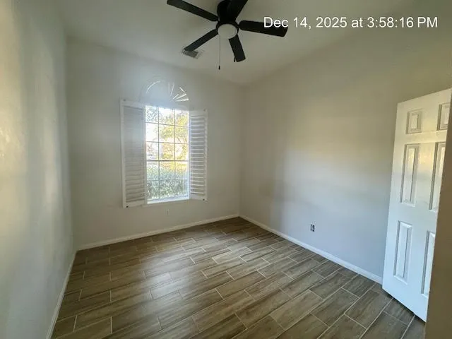 a view of empty room with wooden floor and fan