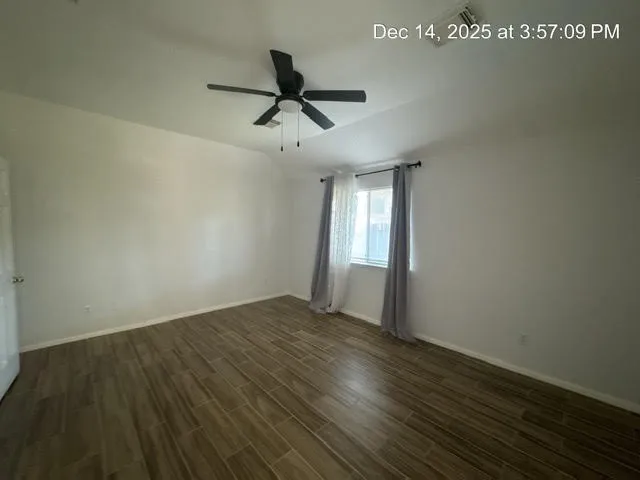a view of empty room with wooden floor and fan