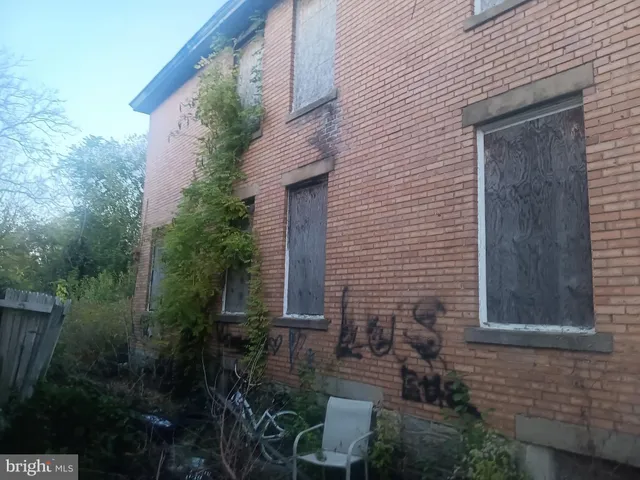 a brick house with a yard plants and large tree