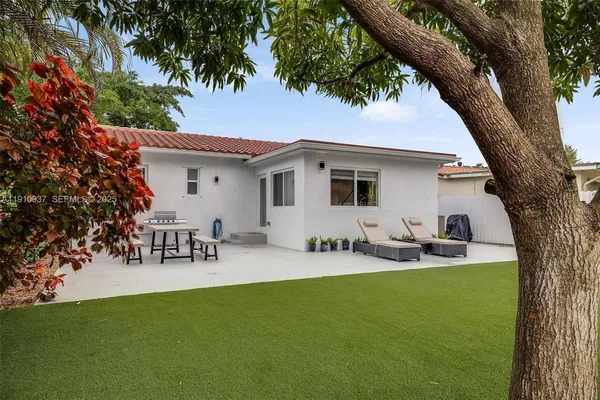 a view of a patio with table and chairs and a large tree