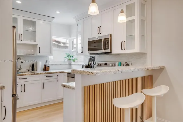 a kitchen with stainless steel appliances a sink a stove a refrigerator cabinets and a dining table