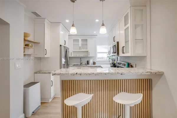 a kitchen with stainless steel appliances granite countertop a sink a stove a kitchen island with a dining table and chairs