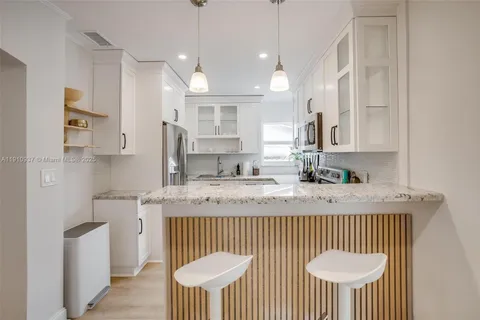 a kitchen with stainless steel appliances granite countertop a sink a stove a kitchen island with a dining table and chairs